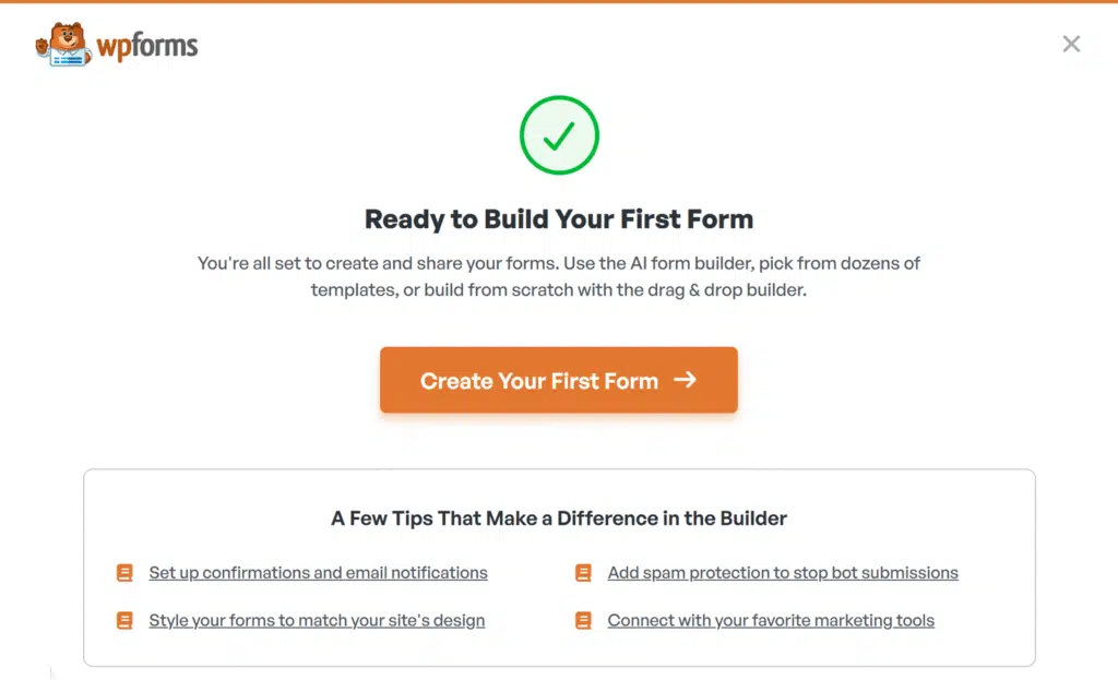 WPForms welcome screen with a green check icon, heading 'Ready to Build Your First Form' and orange 'Create Your First Form' button, plus WPForms logo at top left.