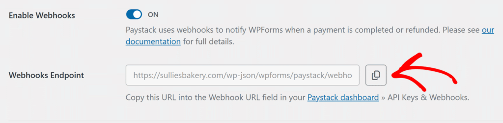 Webhooks settings: toggle ON, explanatory text about Paystack webhooks, a URL in a text field labeled Webhooks Endpoint, and a Copy button highlighted by an arrow